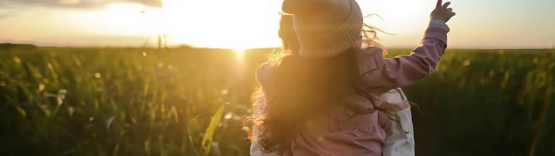 Bildet av en voksen og et barn som ser på en solnedgang